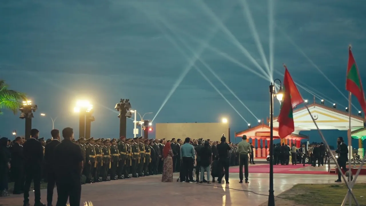 Honour guard and guests at a flag ceremony at dusk in Malé