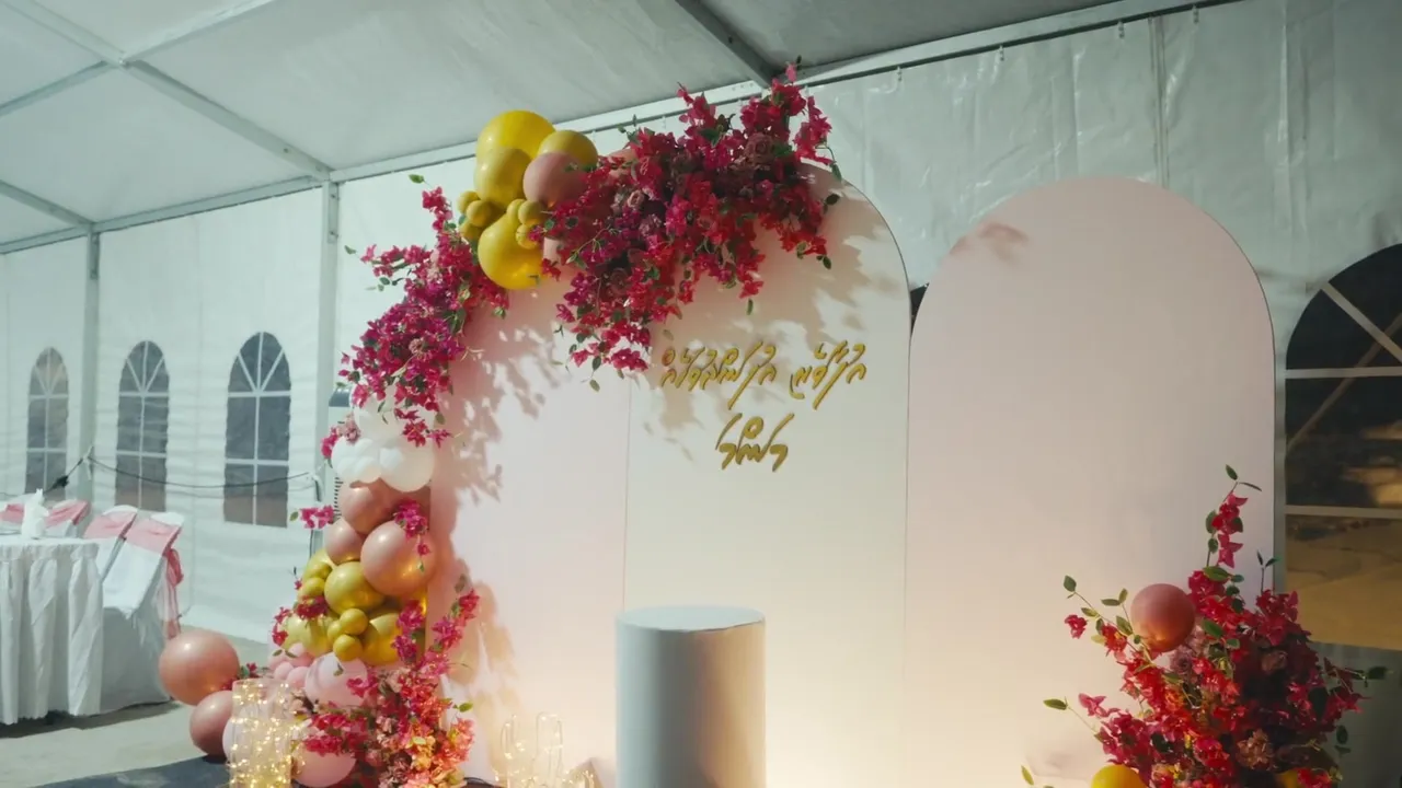 Floral arch and dining tables inside a celebration tent