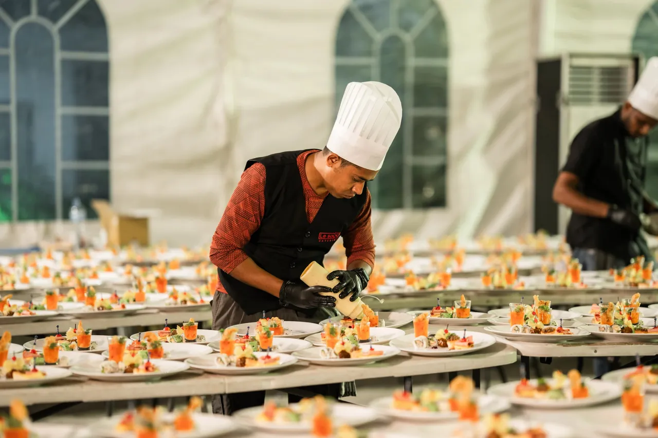 A Le Souq chef plating hundreds of starters in an event tent