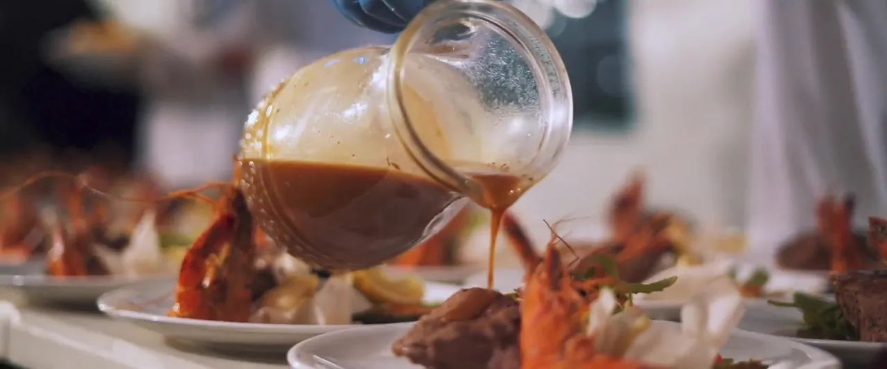 Sauce poured over a plated seafood course